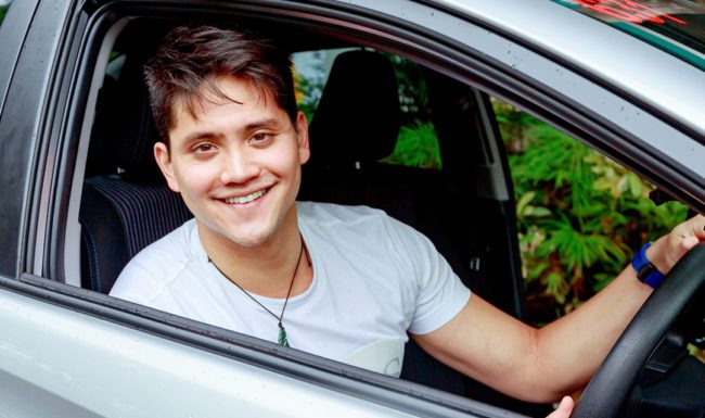 A person smiling at the camera in the car.