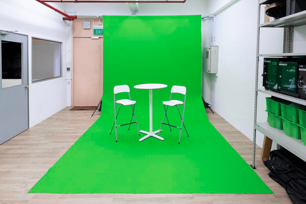 A Studio With Green Backdrop, Two Seats & A Table