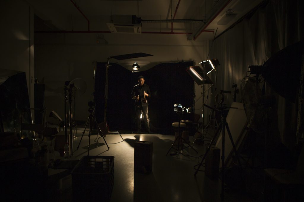 A Dark Studio With A Man In Front Of The Backdrop