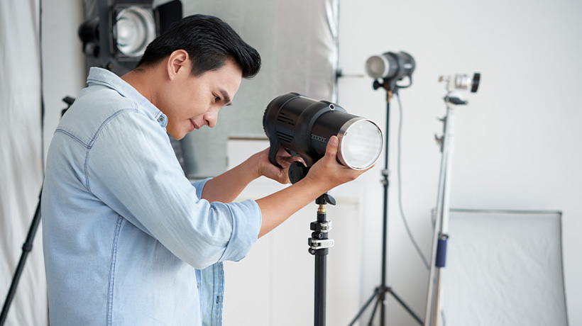 A photographer adjusting a studio light for a photoshoot.