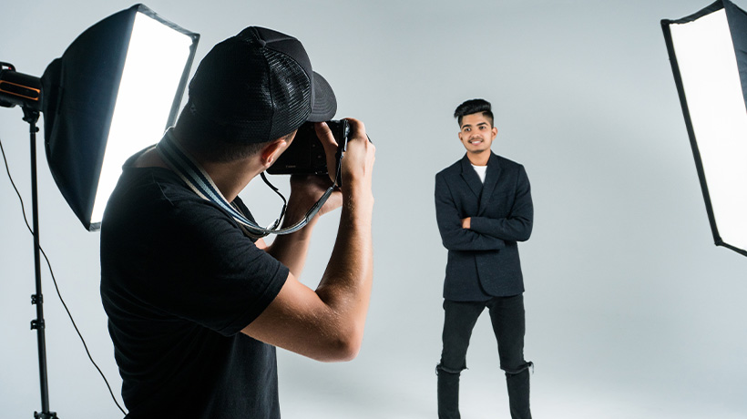 A photographer taking a professional portrait of a man in a studio.