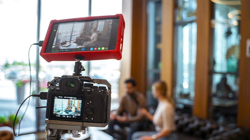 Professional video setup in modern studio with camera and monitor capturing two people in conversation