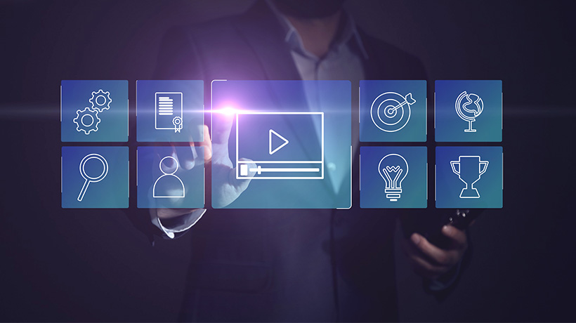 Person in suit interacting with digital interface, selecting video icon among grid of tech-related symbols.