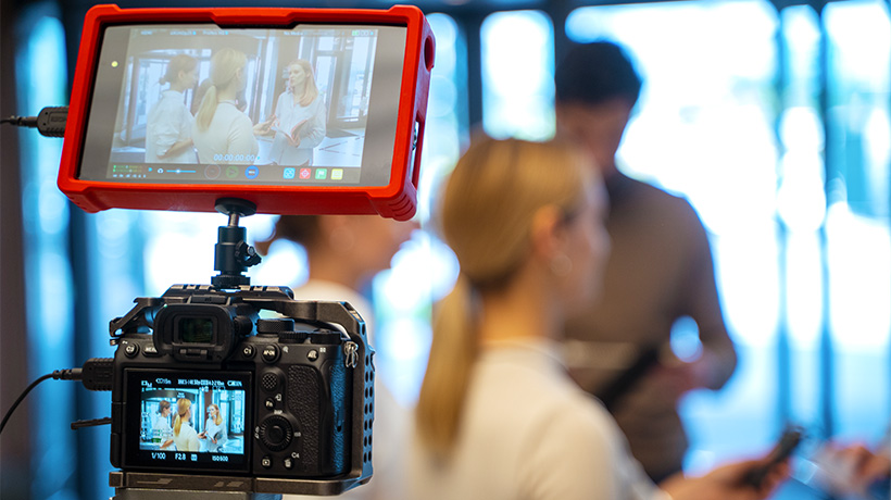 Camera setup with monitor showing interview scene and blurred background.