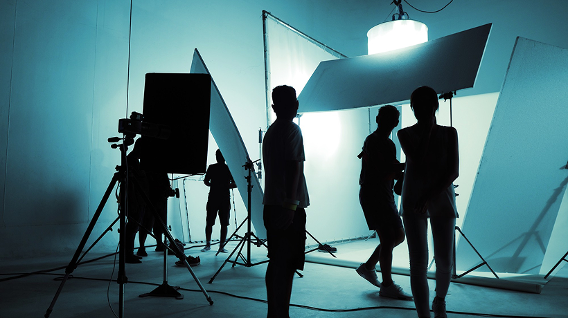 Production crew setting up professional lighting in a studio.
