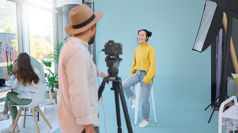 A behind-the-scenes view of a creative studio setup with a photographer and a model